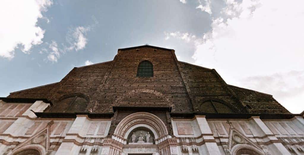 One of the best landmarks in Italy is the Basilica di San Petronio. It has a light stoned colored base with statues over curved doorways and a dark, simple wood top with one curved window in the center.